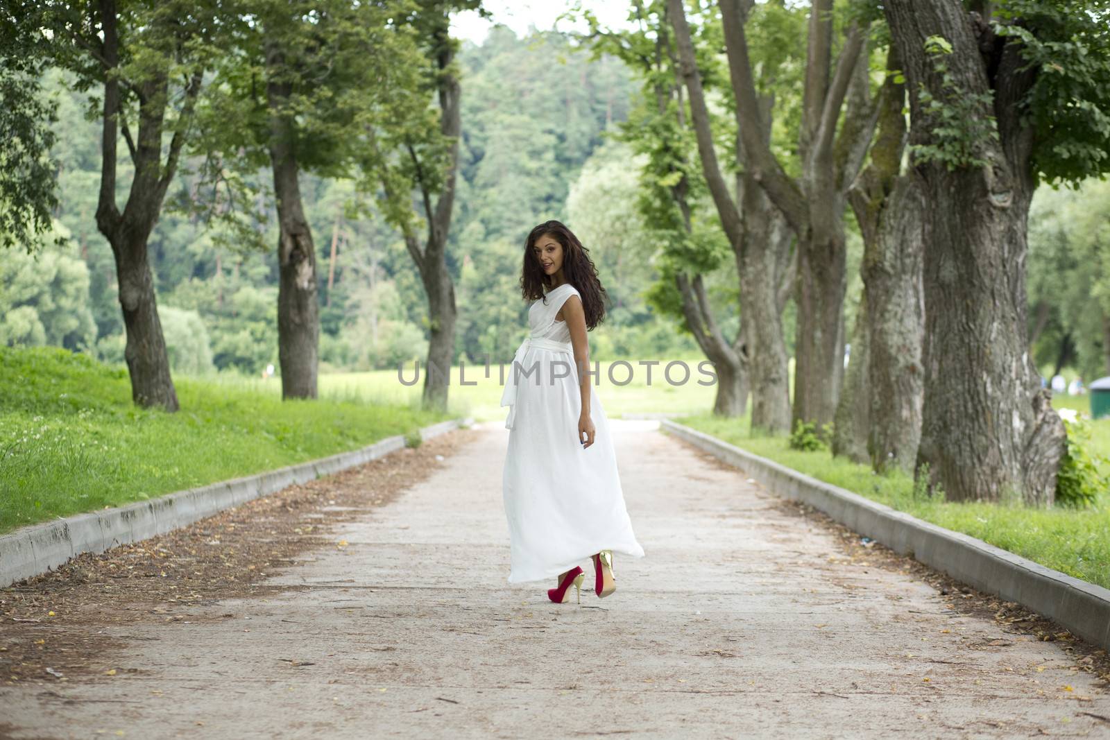Beautiful young woman walking on the summer park