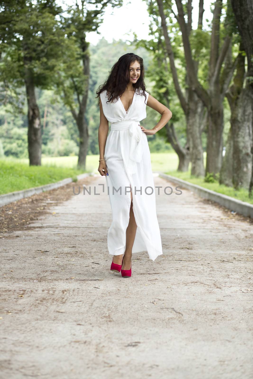 Beautiful young woman walking on the summer park