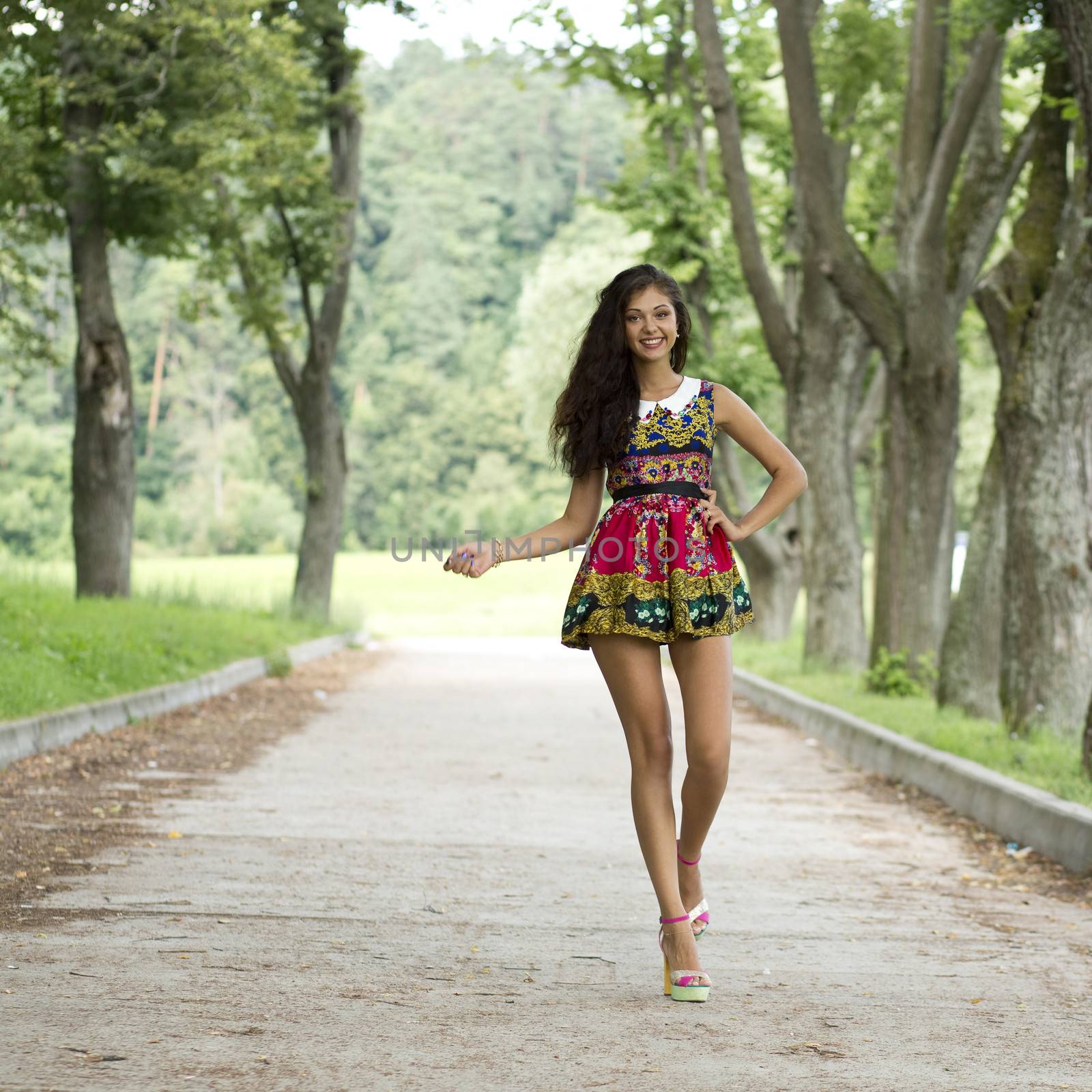 Beautiful young woman walking on the summer park