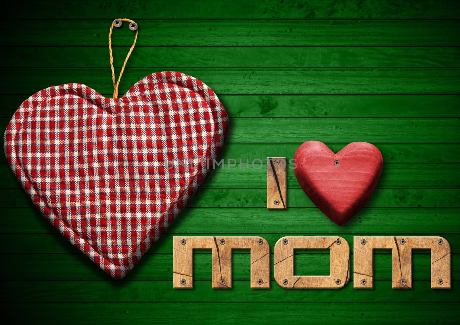 I Love Mom written with wooden letters and red wooden hearts, handmade cloth heart hanging on green wooden background