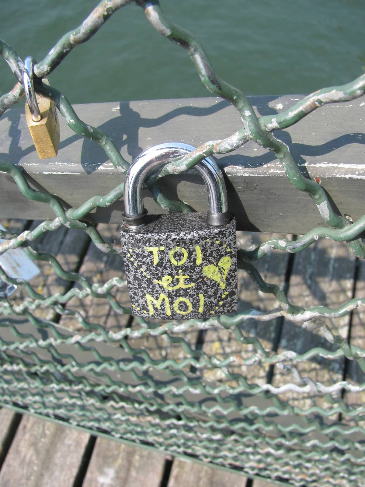 A big padlock hanging on mesh with a message : TOI et Moi , love.