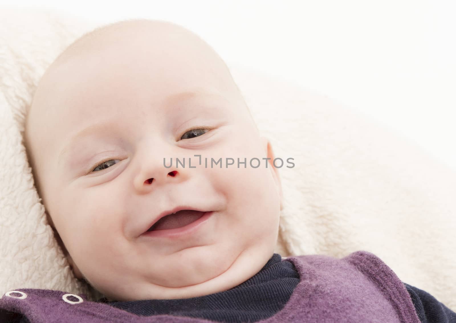 newborn child laughing to camera in horizontal image. studio shot