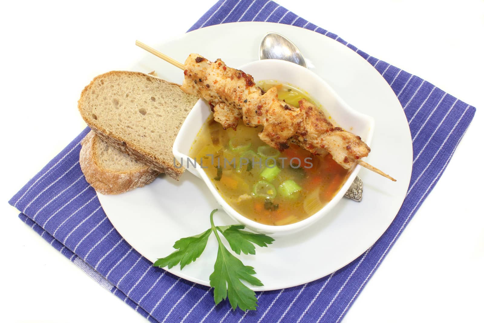 a bowl of chicken consomm� and a chicken skewer