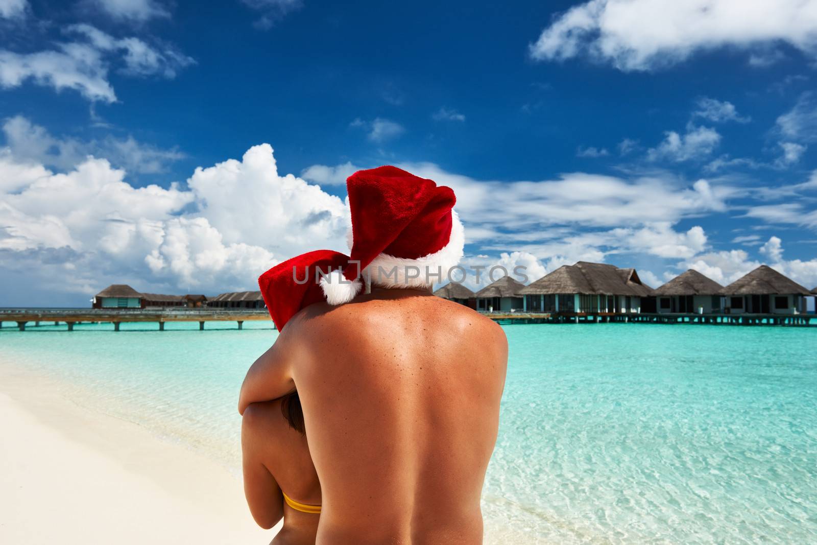 Couple in santa's hat on a tropical beach at Maldives