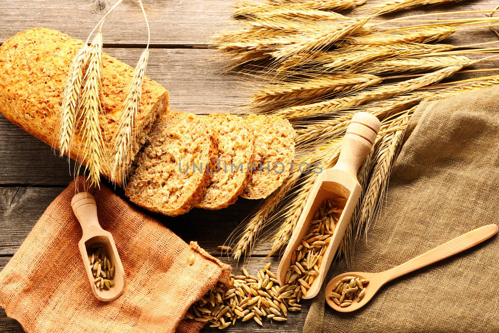 Rye spikelets and bread still life on wooden background by haveseen