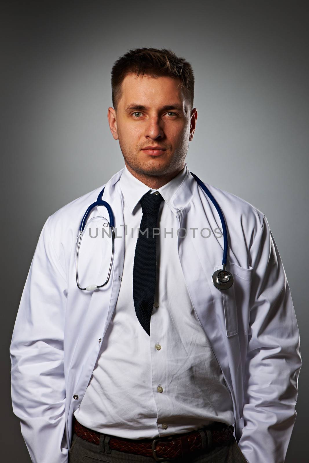 Medical doctor with stethoscope portrait against grey background 