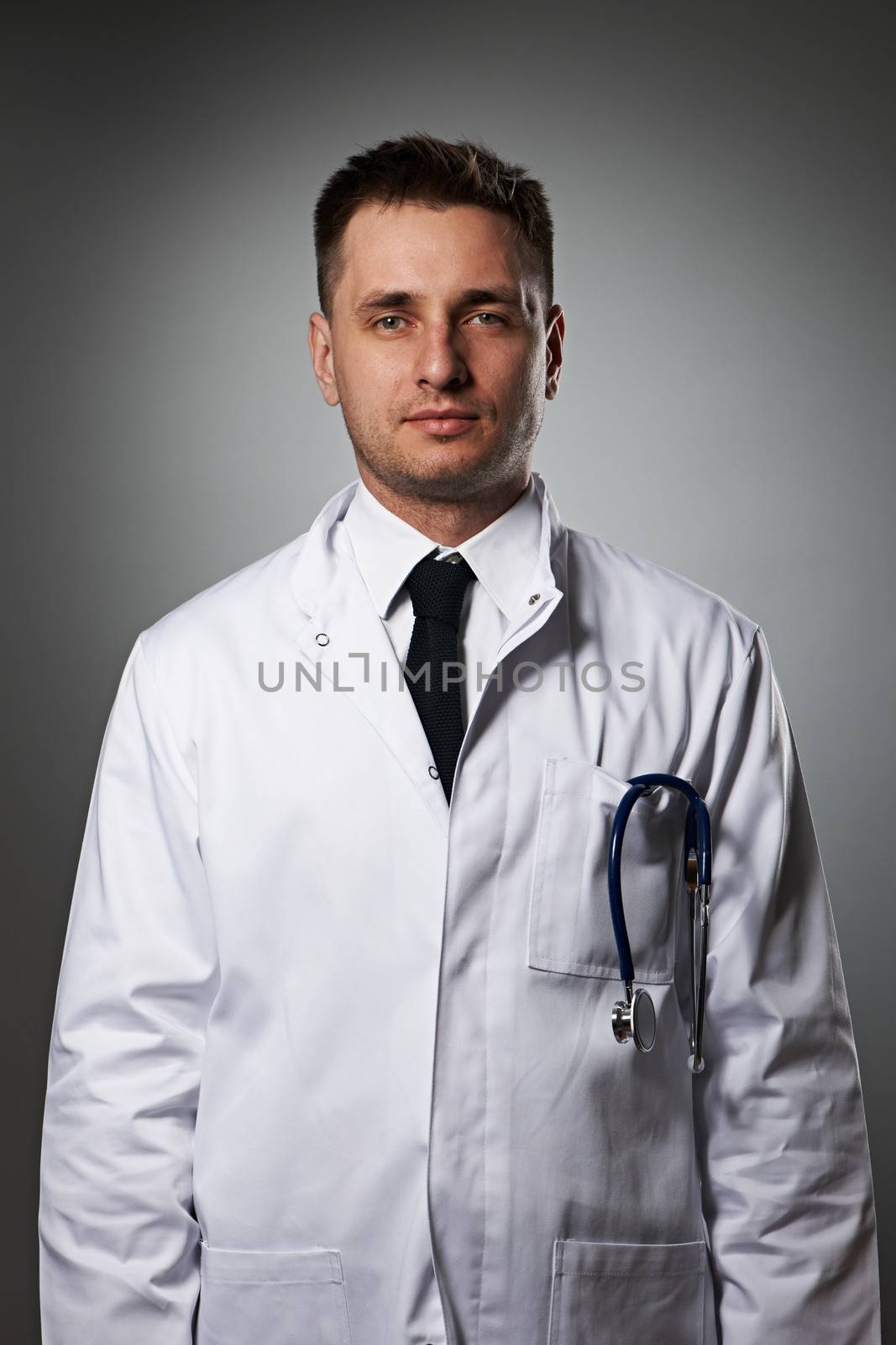 Medical doctor with stethoscope portrait against grey background 