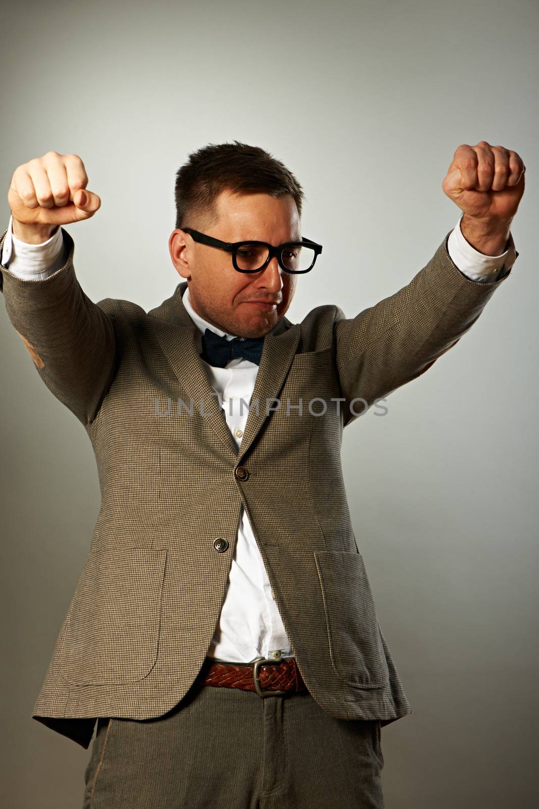 Superhero nerd in eyeglasses and bow tie against grey background