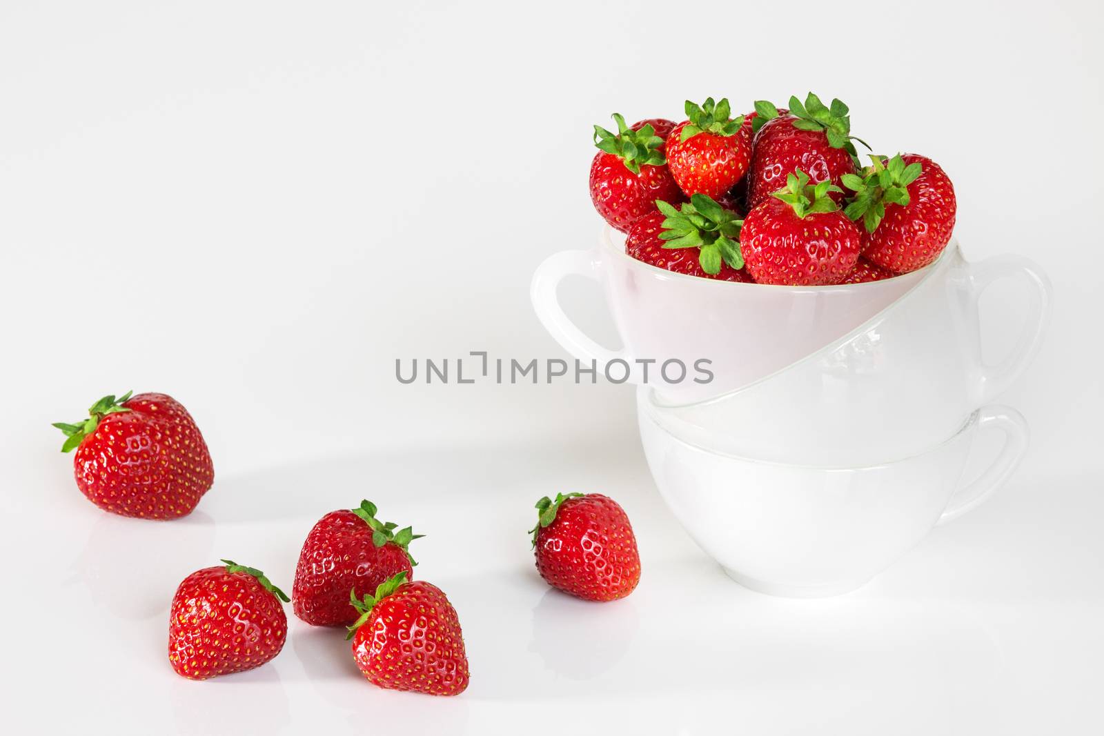 Fresh strawberries in a cup, on white background.