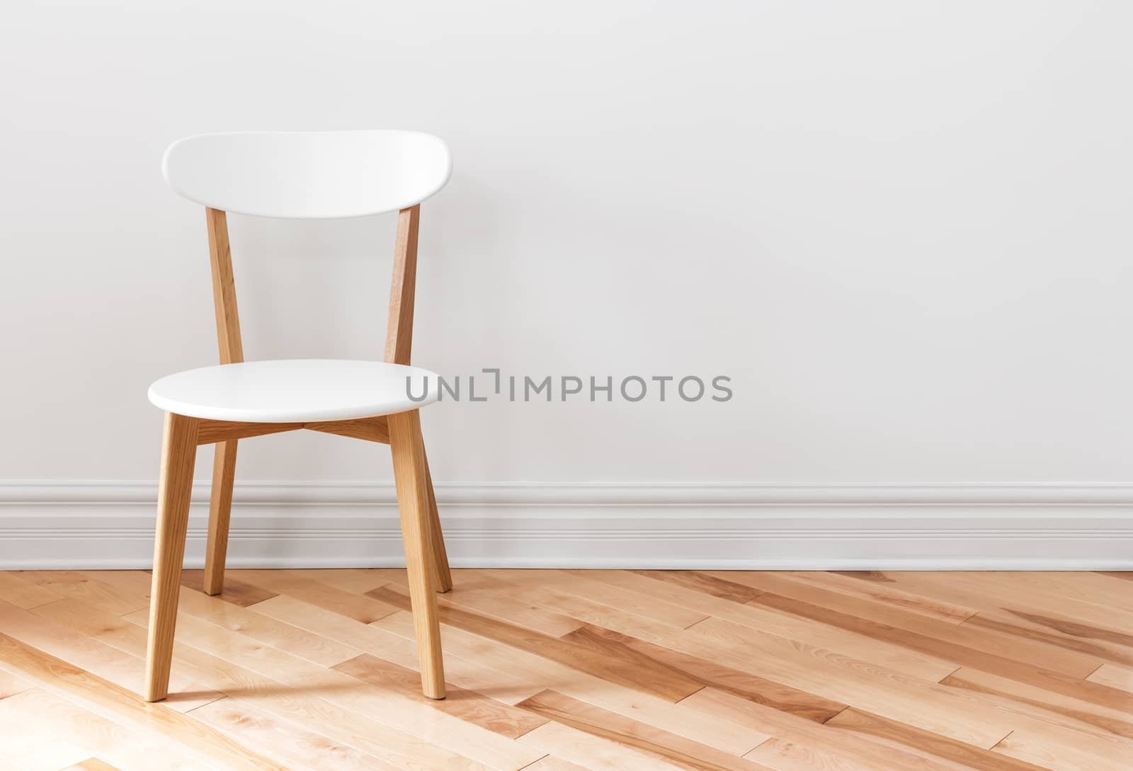 Elegant white chair in an empty room with wooden floor.