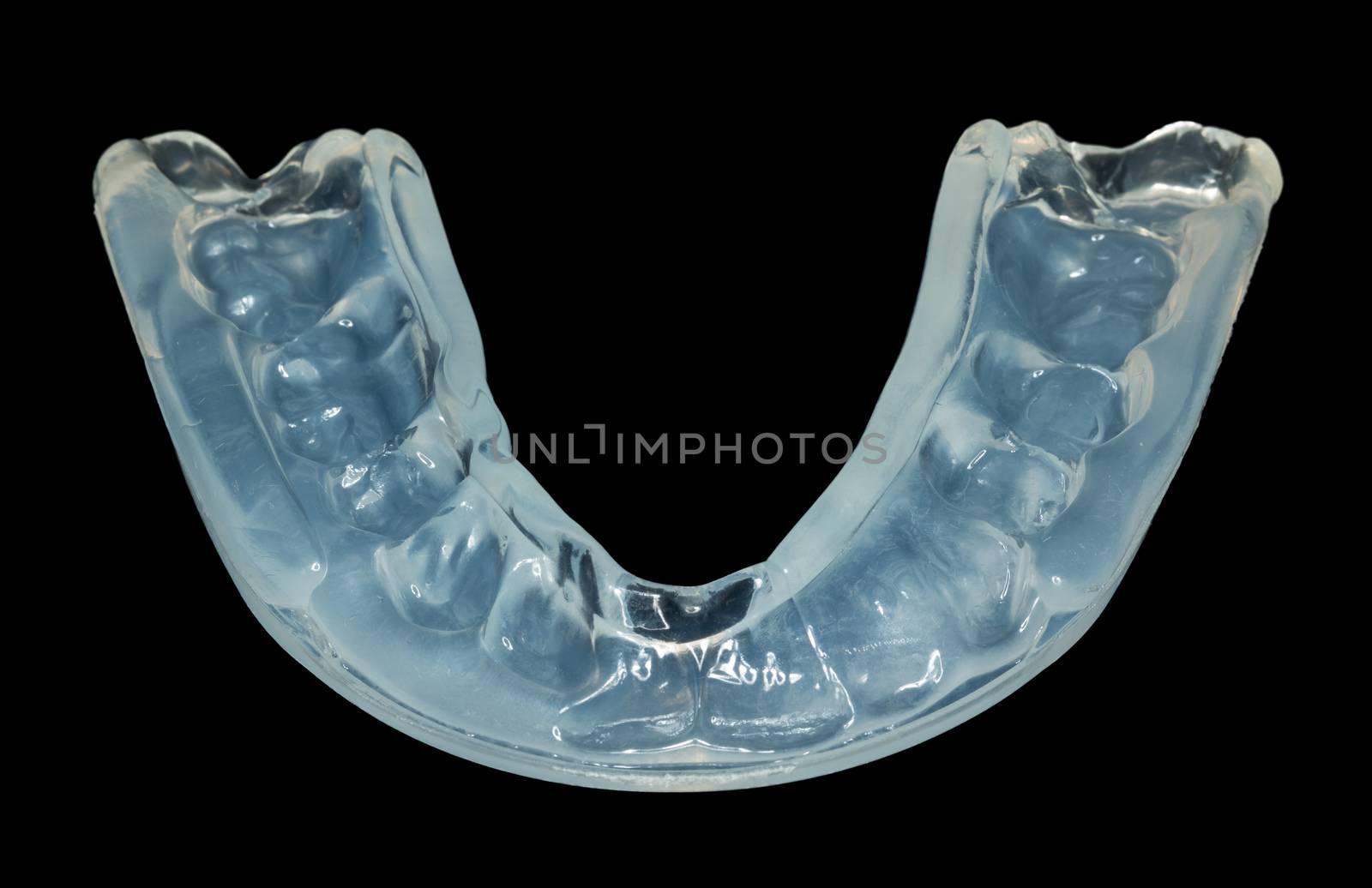Macro close up of a plastic teethguard to stop wear due to teeth grinding at night isolated against black background. Often caused by tension and worry.