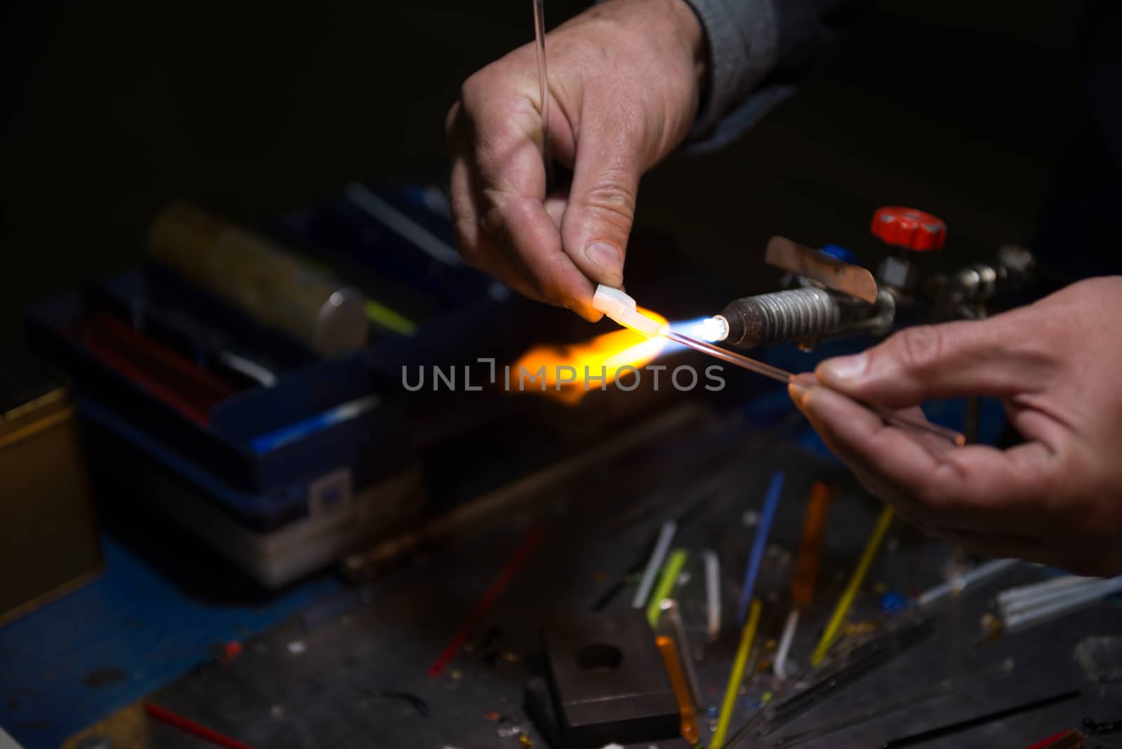 master glassblower shapes the glass warmed by the burner flame