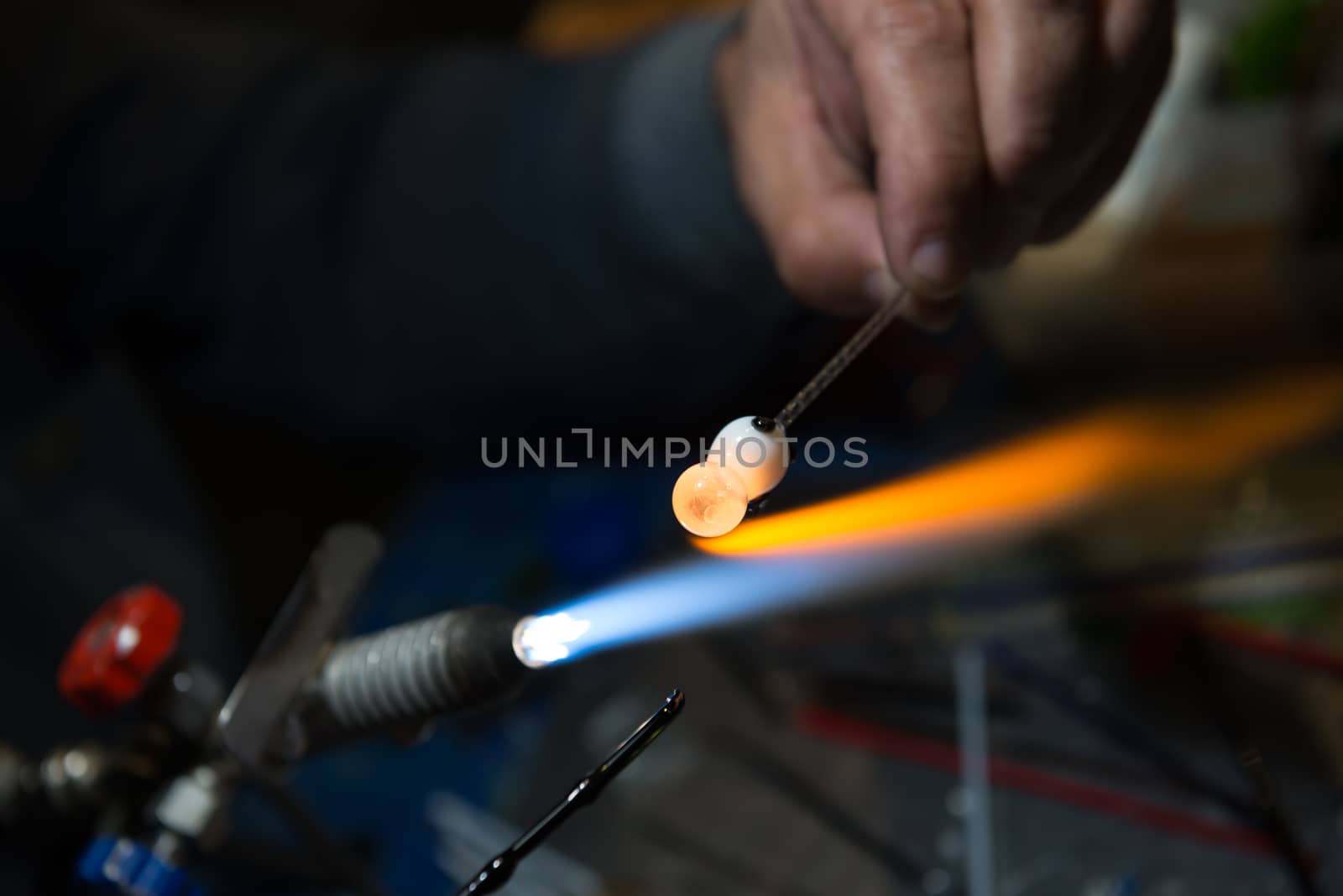 master glassblower shapes the glass warmed by the burner flame