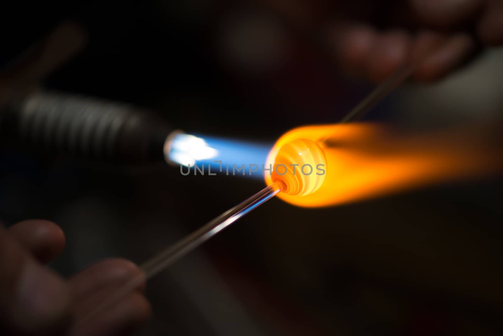 master glassblower shapes the glass warmed by the burner flame