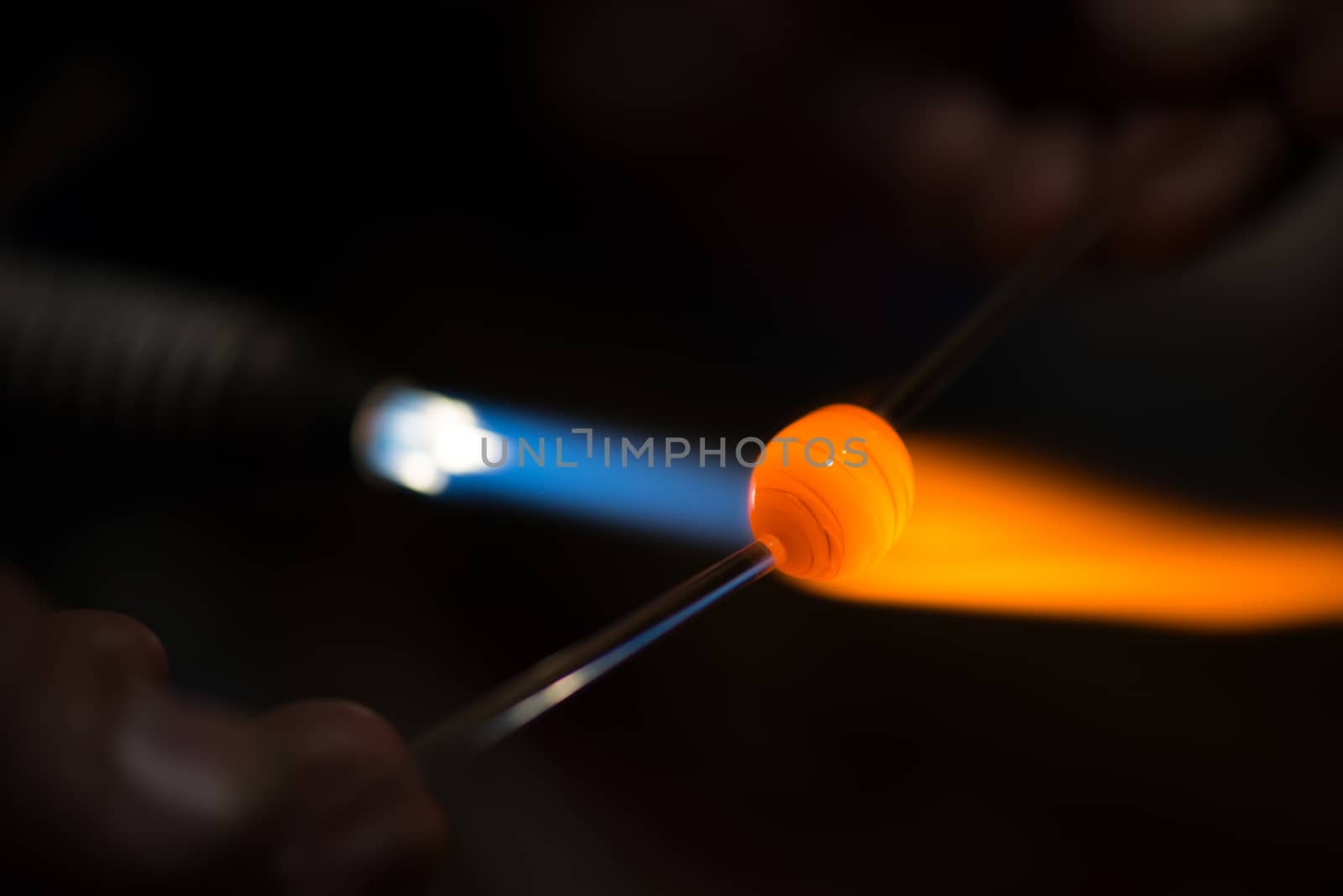 master glassblower shapes the glass warmed by the burner flame