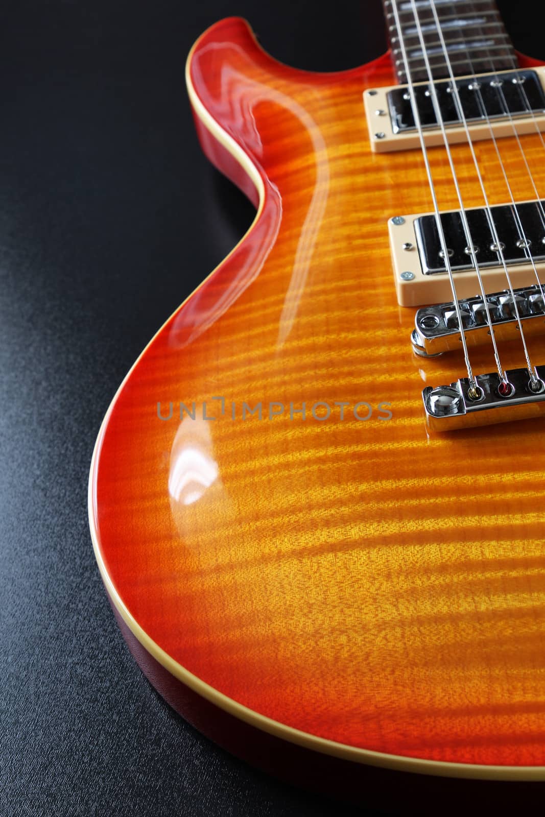 Closeup of electric guitar with cherry sunburst finish and flame maple top.