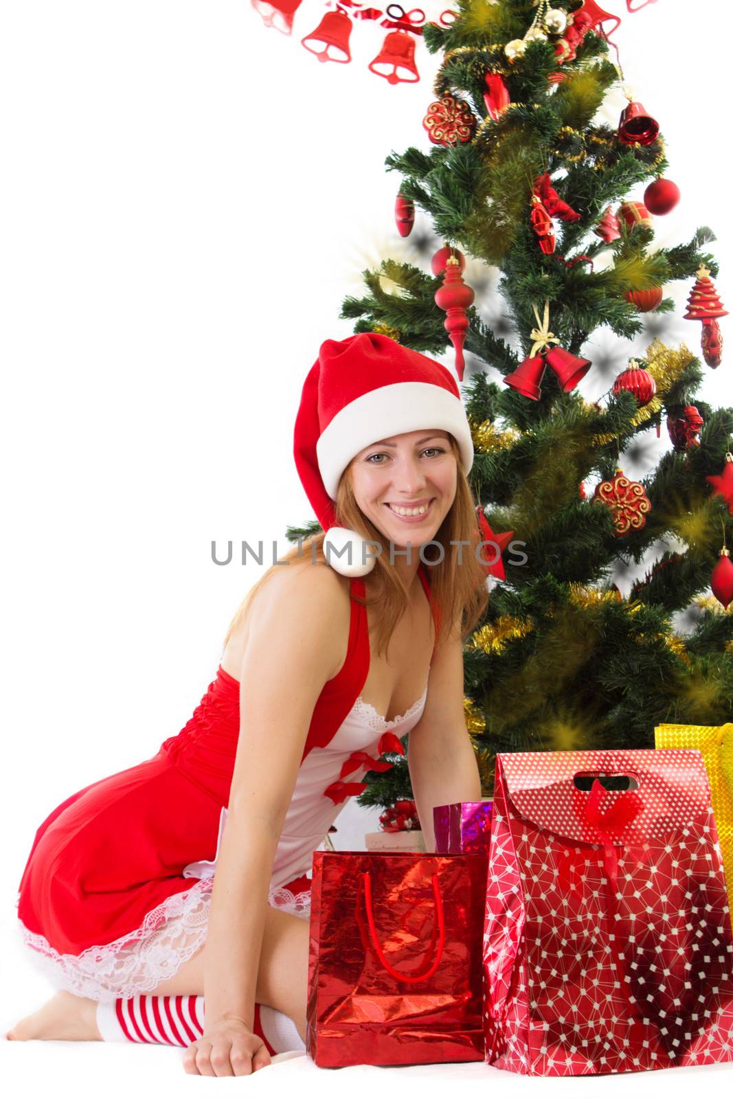 Smiling woman in red sitting under Christmas tree with gifts