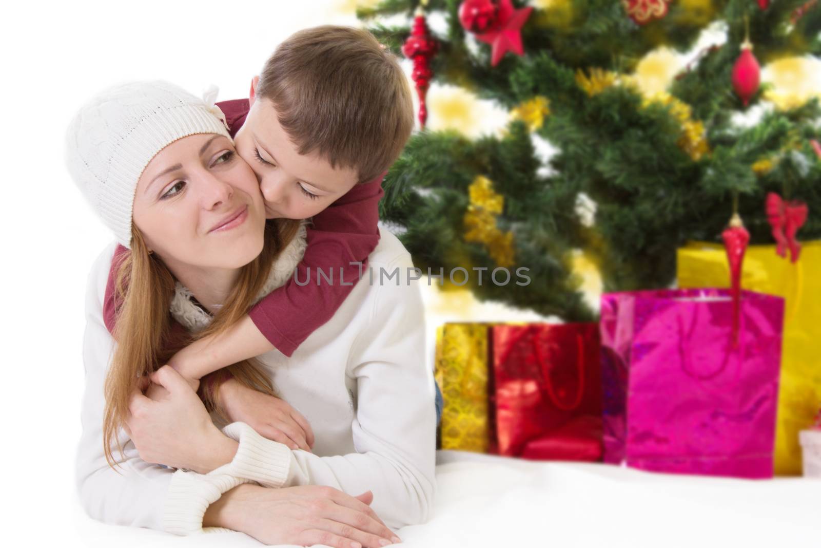 Happy mother with hugging boy under Christmas tree