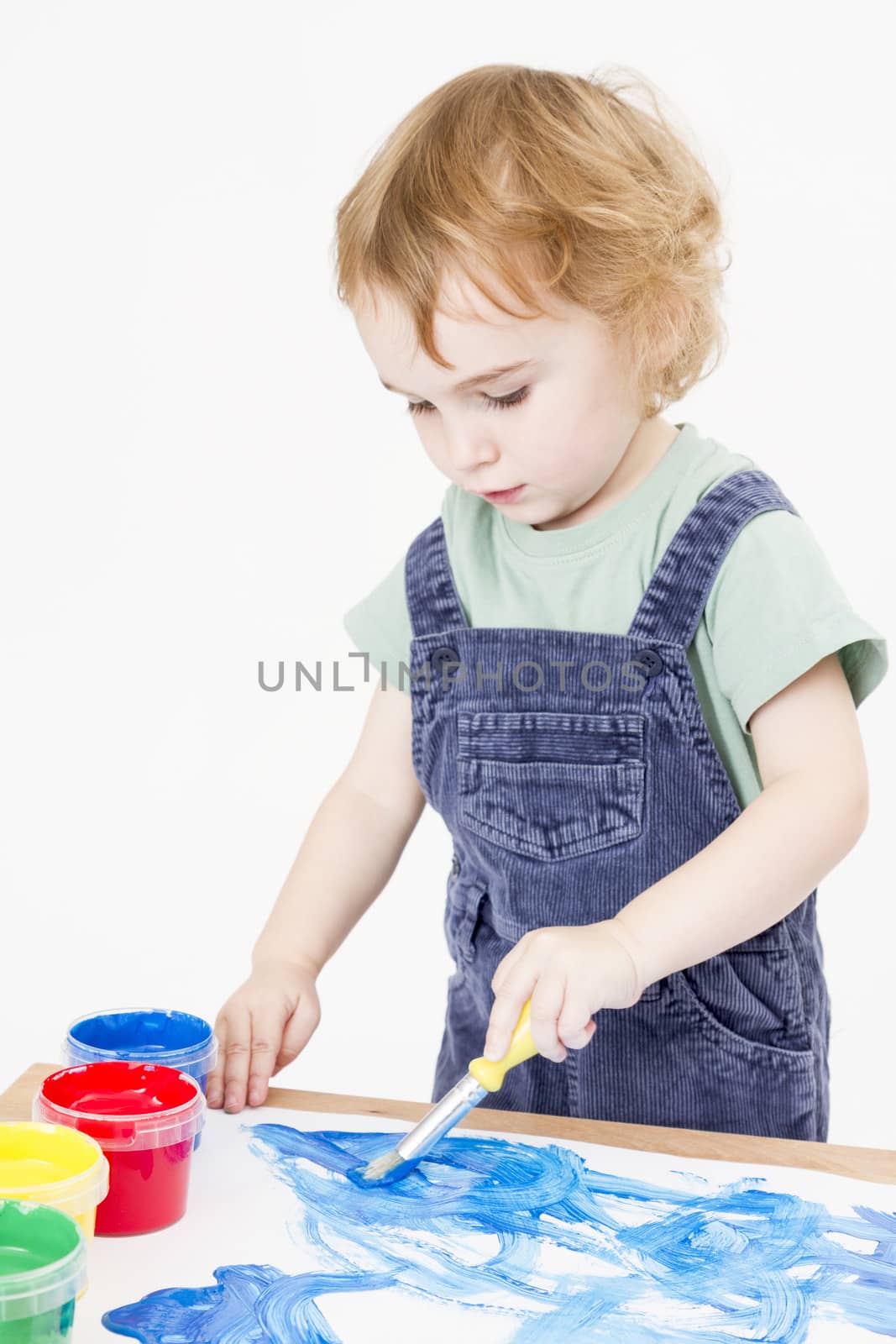 cute child making picture with brush and paint in light background