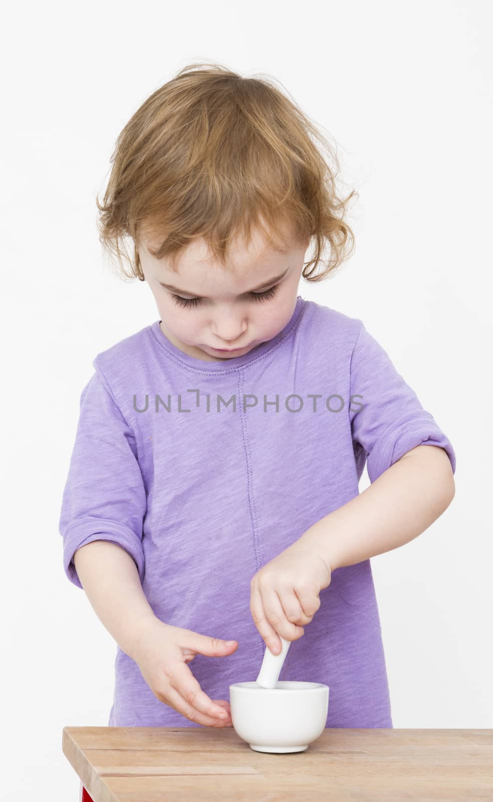 child working with mortar. neutral grey background