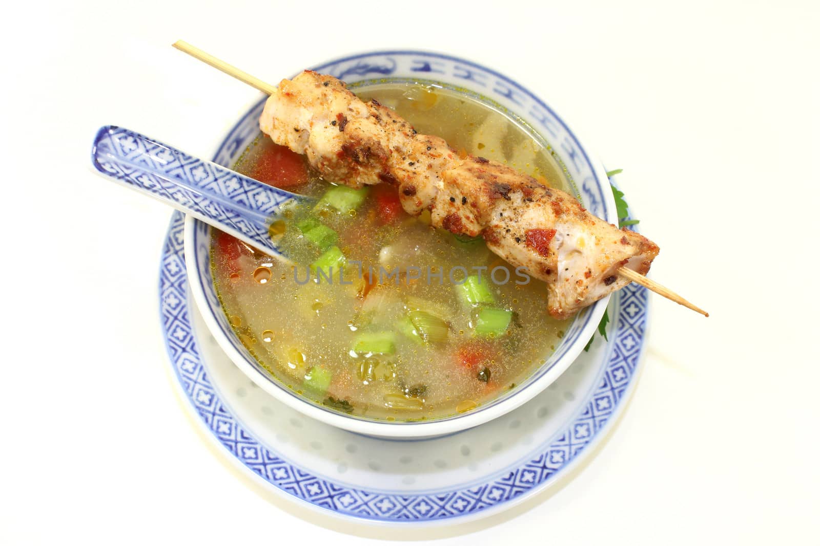 a bowl of chicken consomme and a chicken skewer