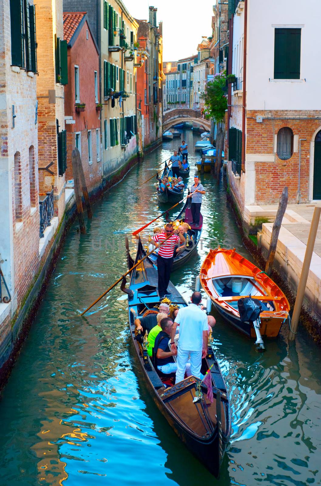 Venice, Italy - September 6, 2013 :  Gondolas with tourists cruising a small Venetian canal. More than 20 million tourists come to Venice annually.