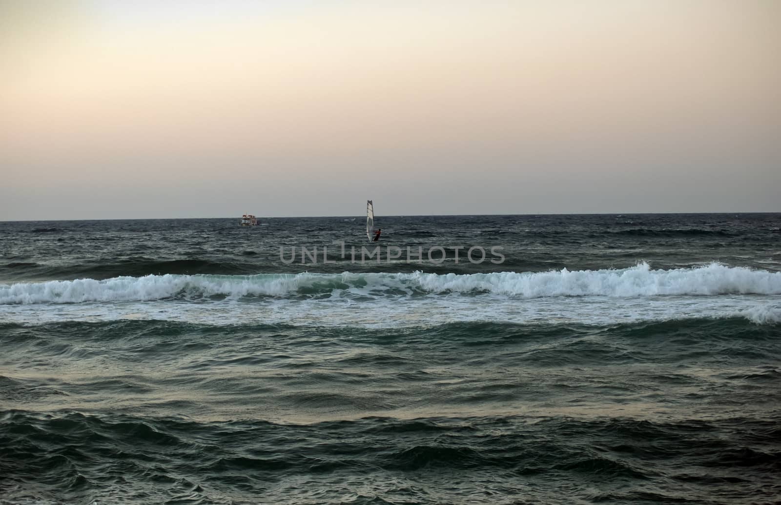 windsurfer silhouette against a sparking blue sea .