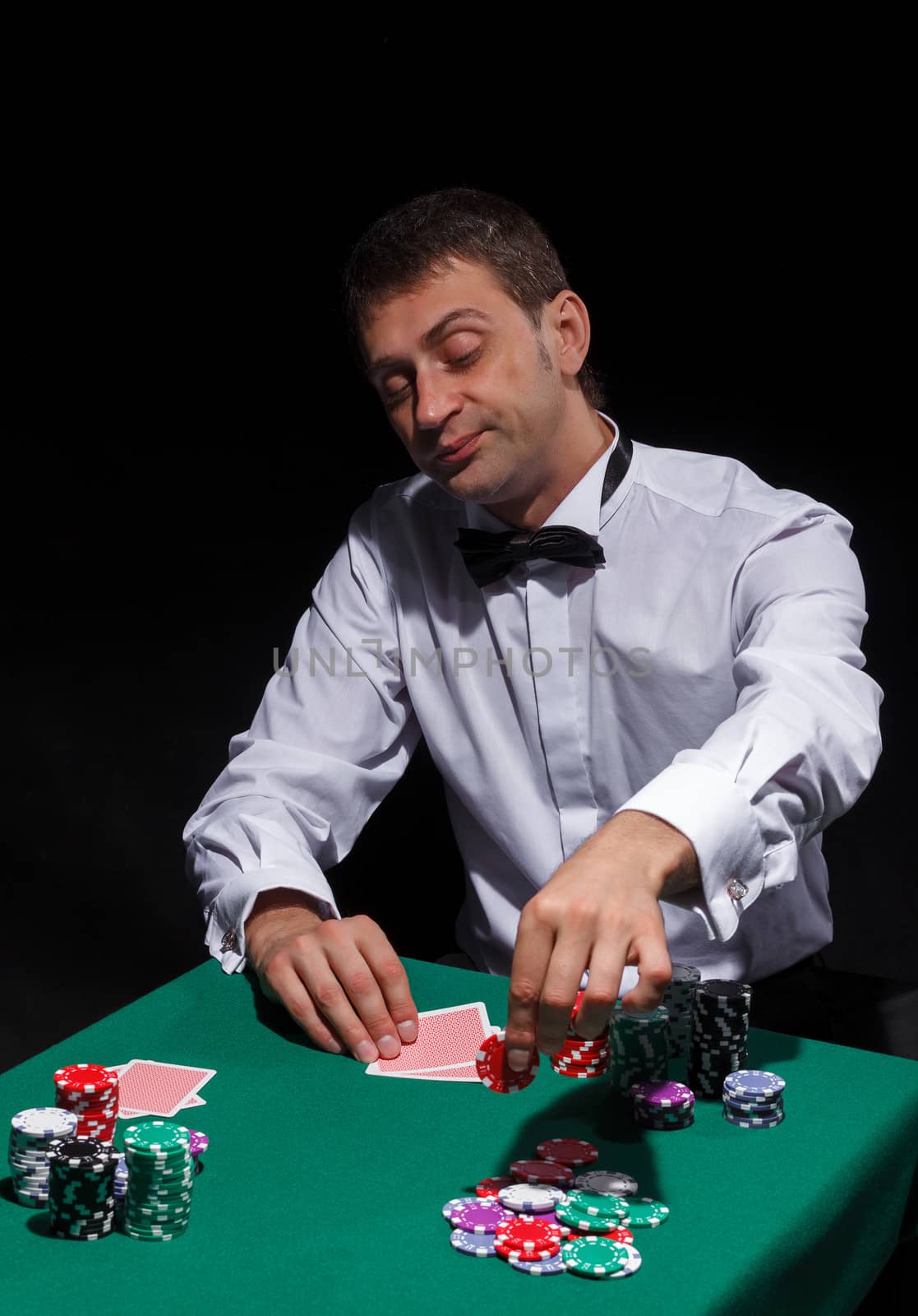 Gentleman in white shirt, playing cards, on black background