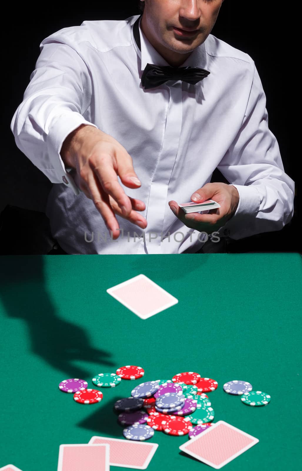 Gentleman in white shirt, playing cards, on black background