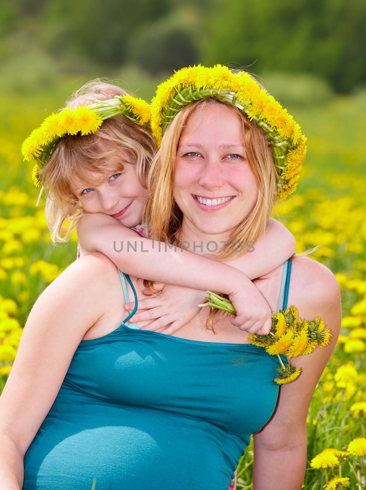 Young pregnant woman with cute little girl enjoying a summer day outdoors