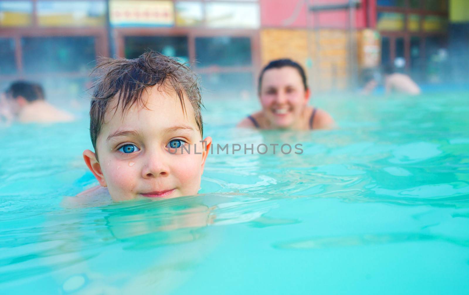 Activities on the pool. Portrait of cute boy with mother relaxing in termal swimming pool