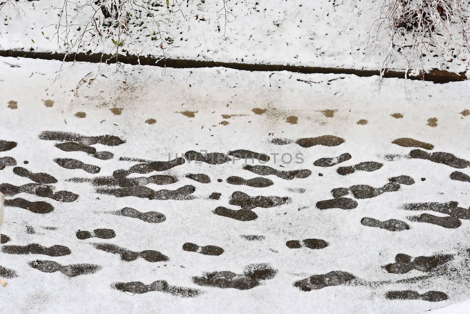 footprints at snowy sidewalk by anvodak