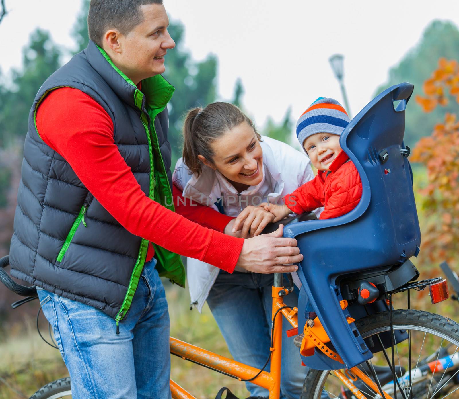 Family with baby on bikes in the autumn park.