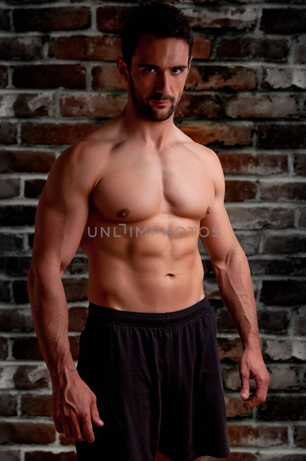Male model looking mean and dangerous with a brick dark background