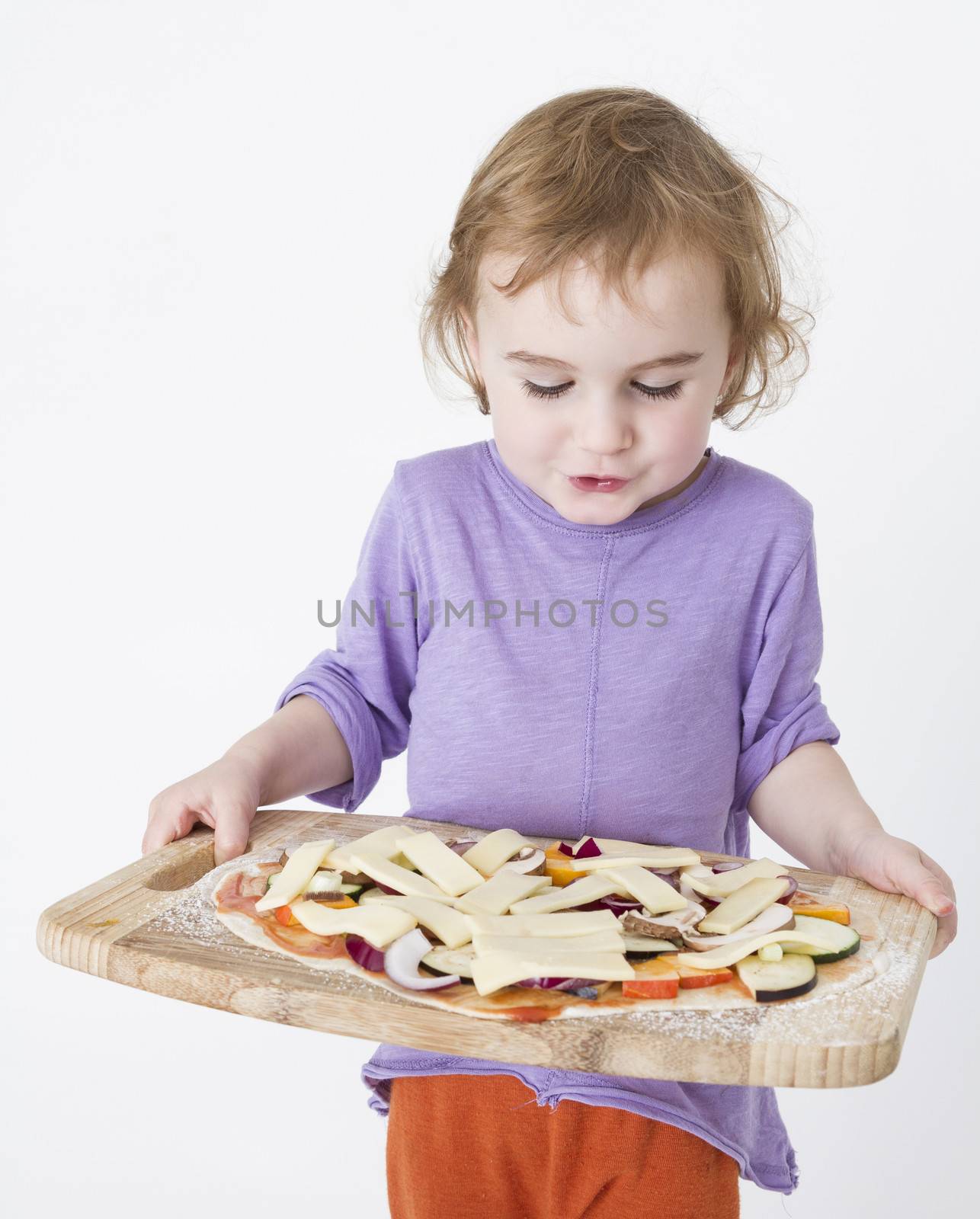 child carrying fresh pizza to the oven. studio shot in grey background