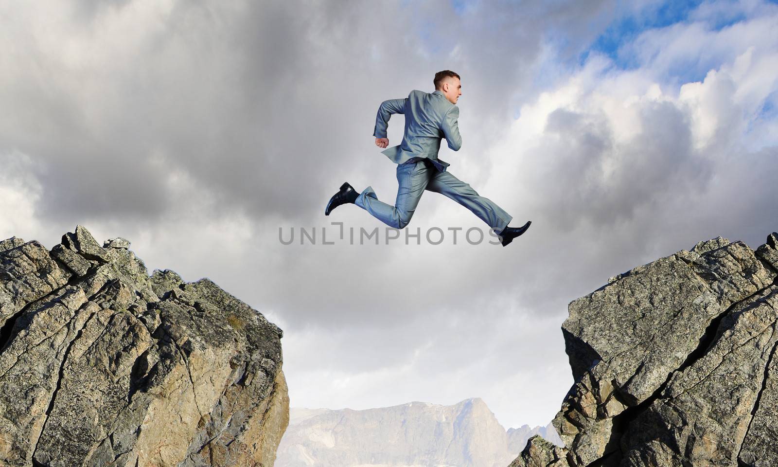 Image of young businessman jumping over gap