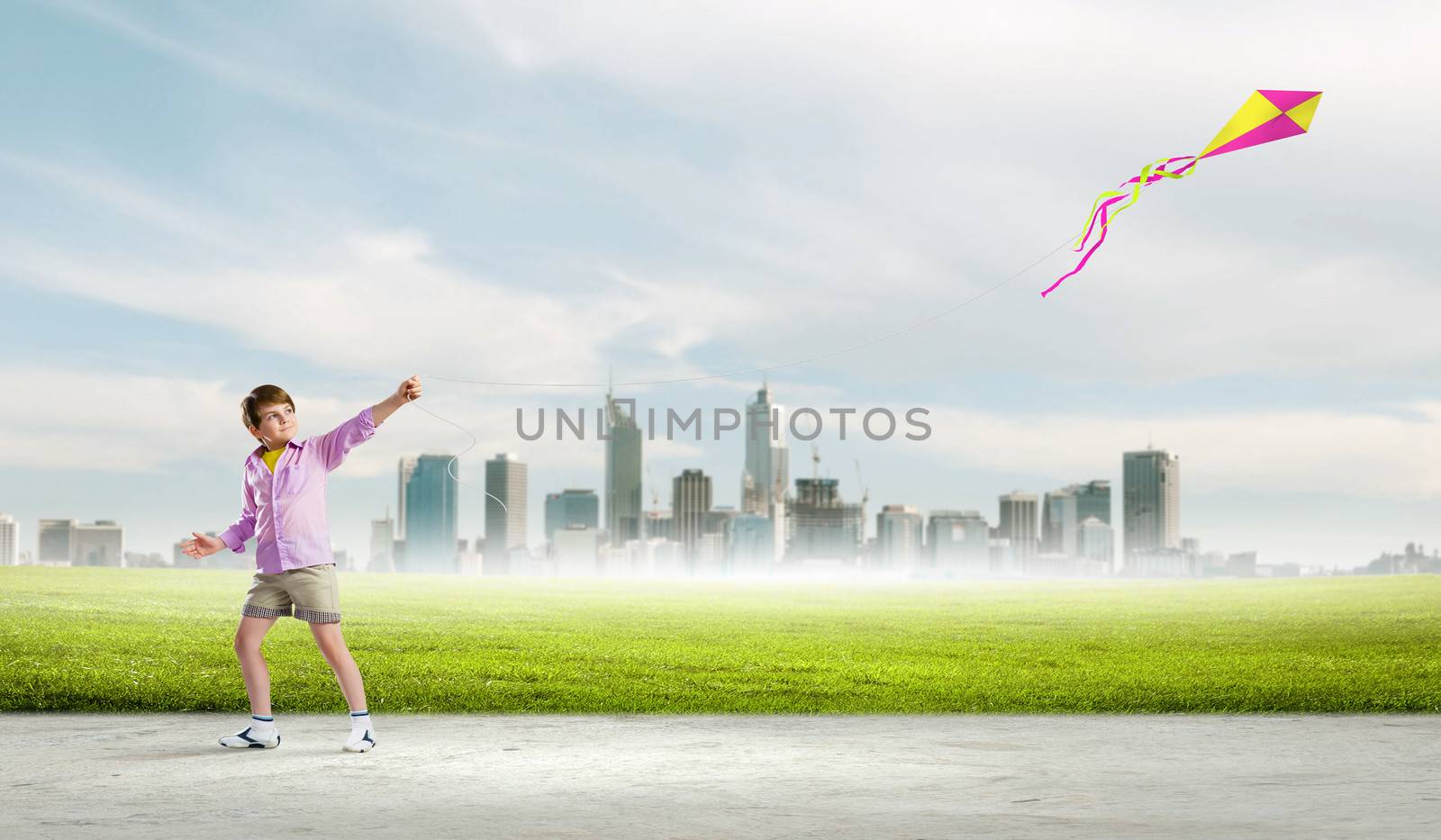 Little boy playing with kite on meadow. Childhood concept