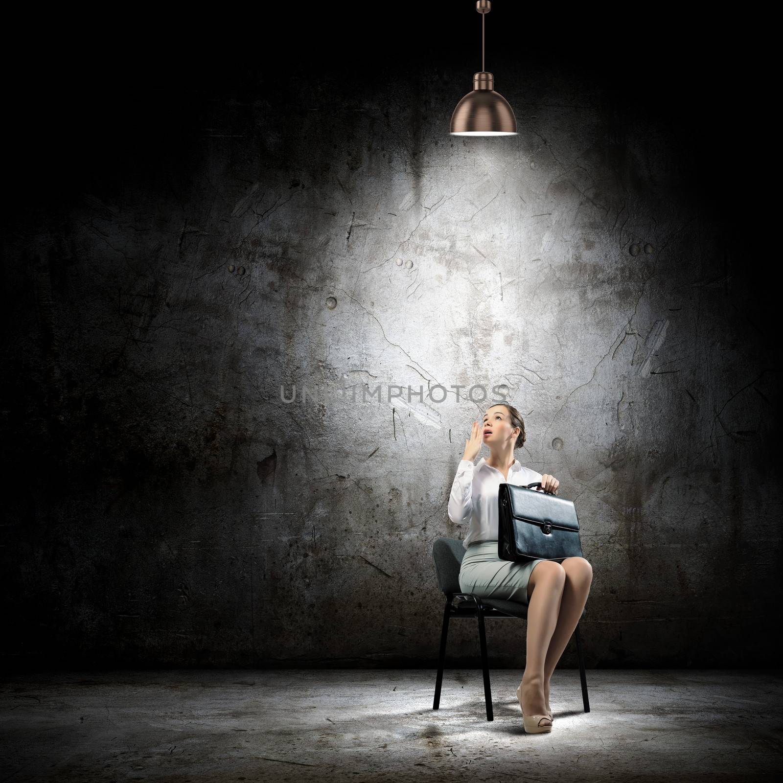 Image of young businesswoman sitting on chair under spot of light