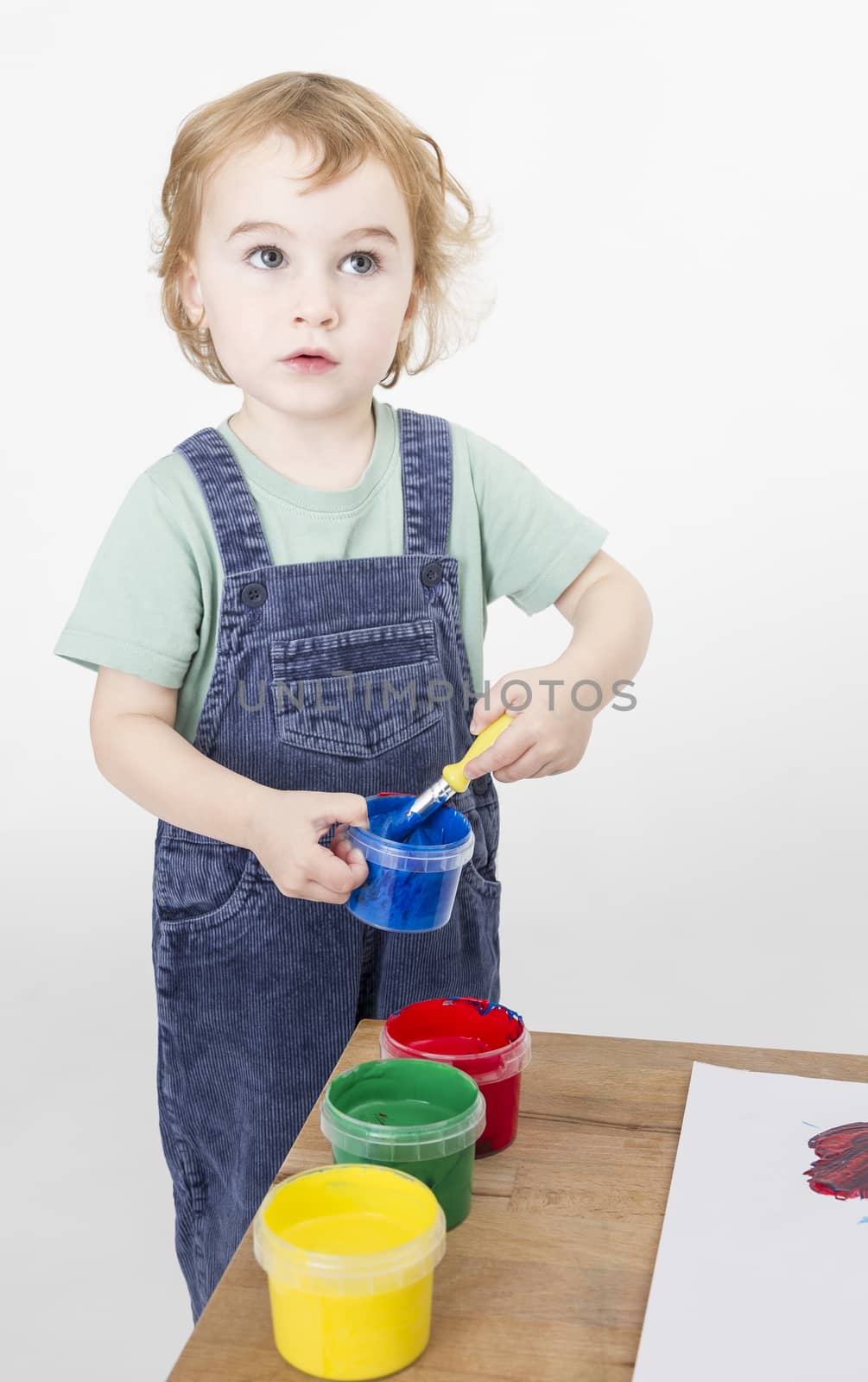 little girl with brush in paint tub. studio shot on light grey background