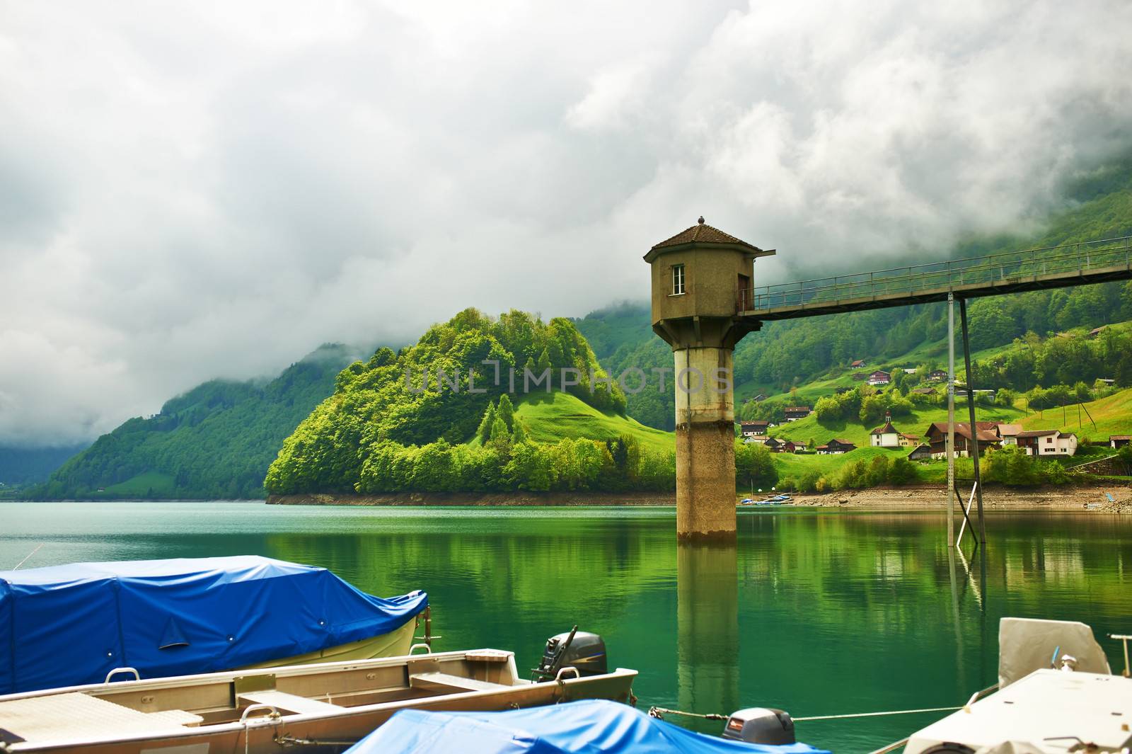 Beautiful emerald mountain lake in Switzerland under low clouds