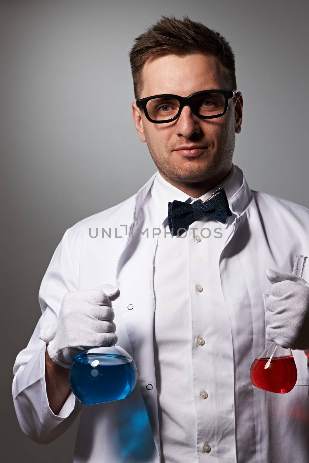 Scientist with chemical flasks against grey background