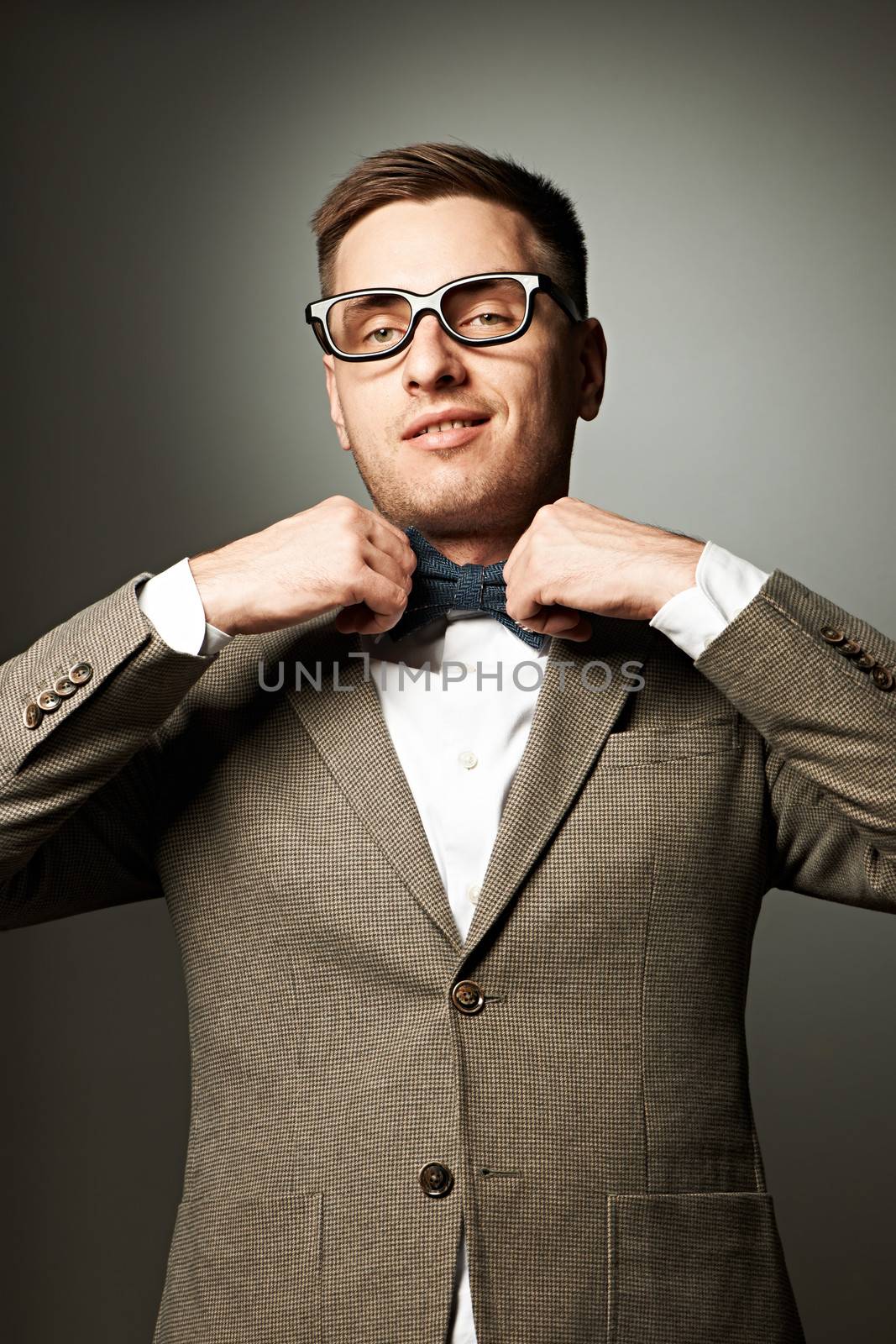 Confident nerd in eyeglasses adjusting his bow-tie by haveseen