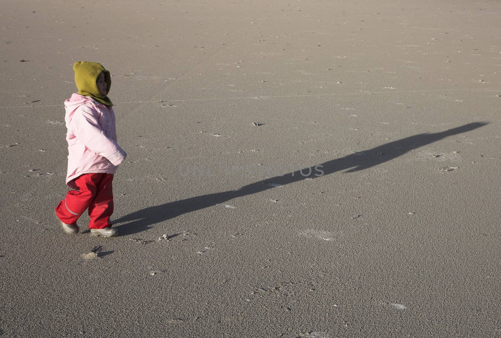 small girl running on a beach in denmark in winter