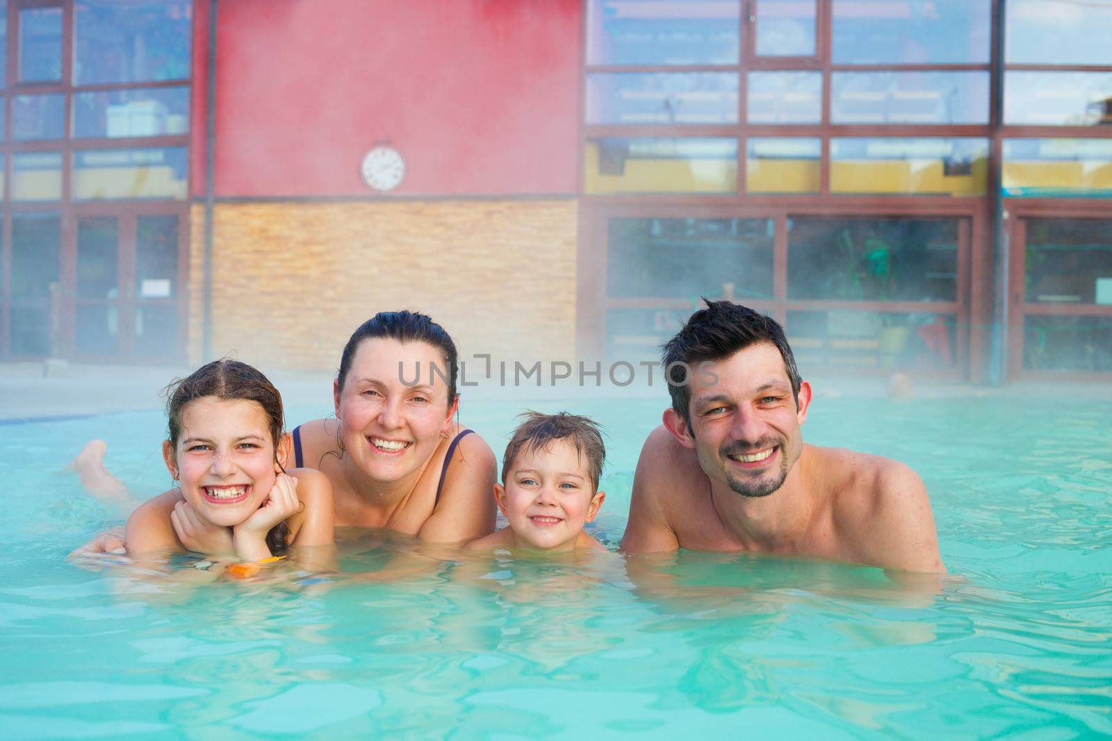 Activities on the pool. Portrait of happy family of four relaxing in termal swimming pool