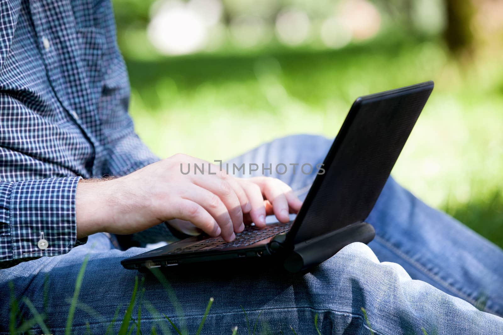 Hands of businessman working with laptop in the park.