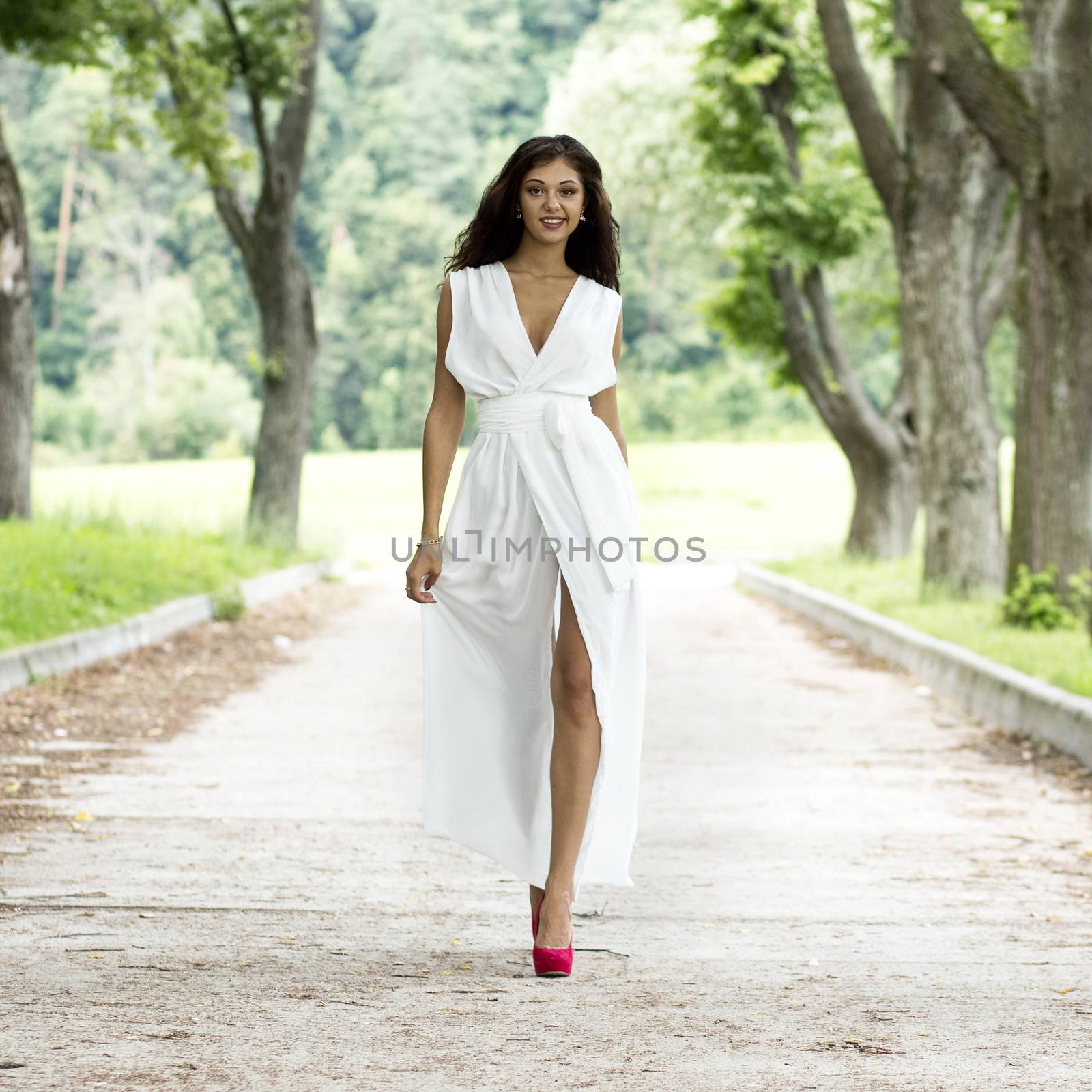 Happy young woman walking on the summer park by andersonrise