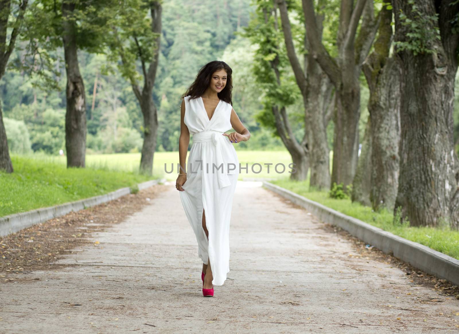 Beautiful young woman walking on the summer park