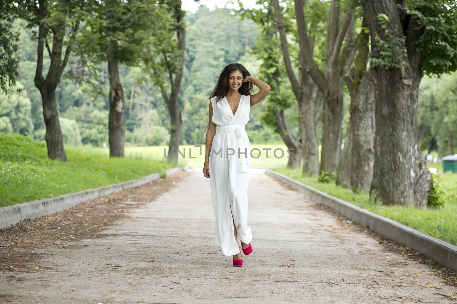 Beautiful young woman walking on the summer park