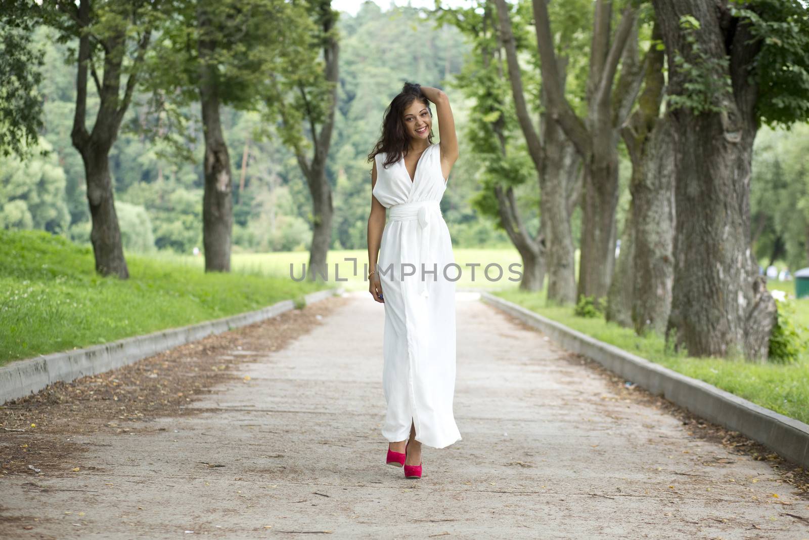 Beautiful young woman walking on the summer park