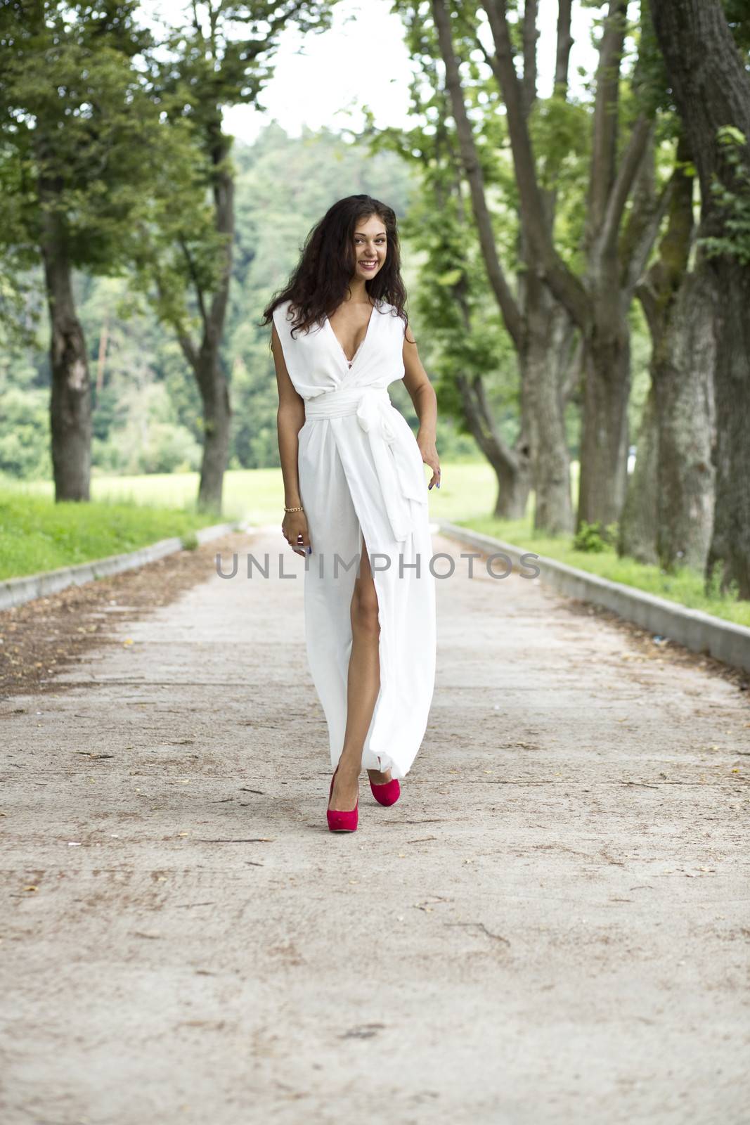 Beautiful young woman walking on the summer park